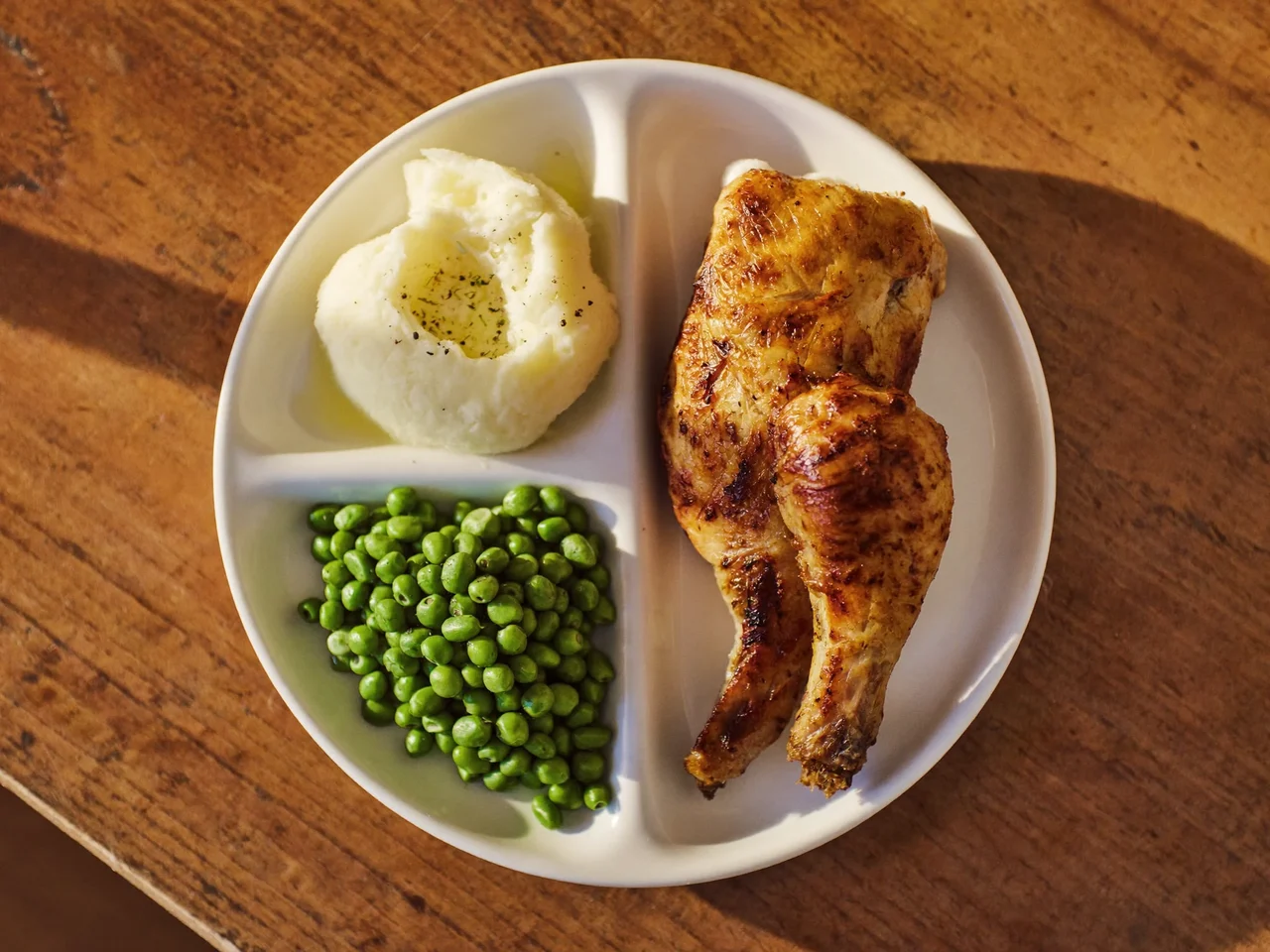 Illustration: roast chicken dinner with mashed potato and soft vegetables in a sectioned tray